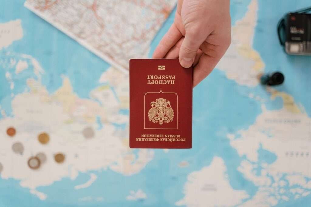A hand holding a Russian passport above a travel-themed map, capturing world travel concepts.